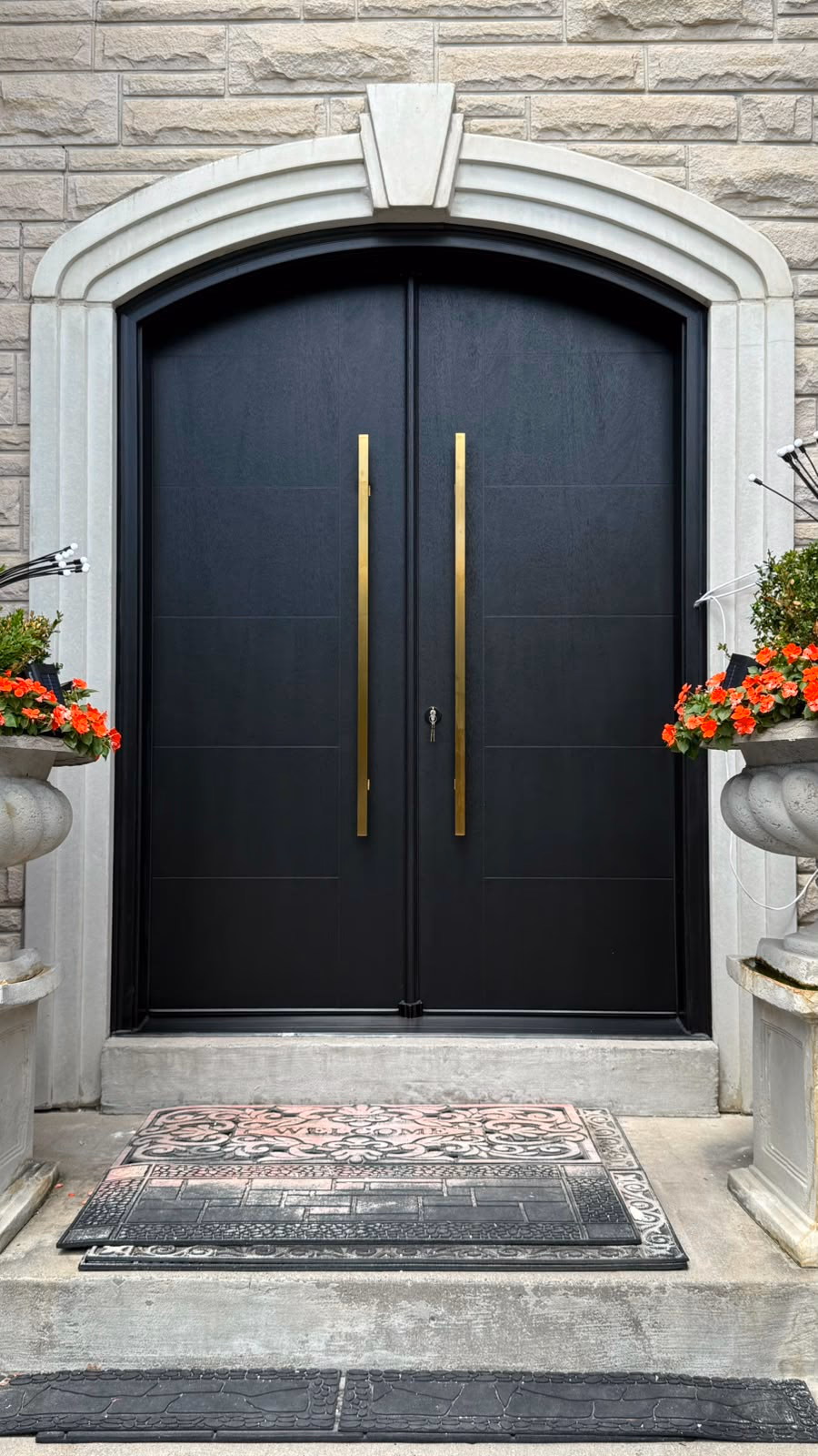 Black arched double entry doors with long gold handles