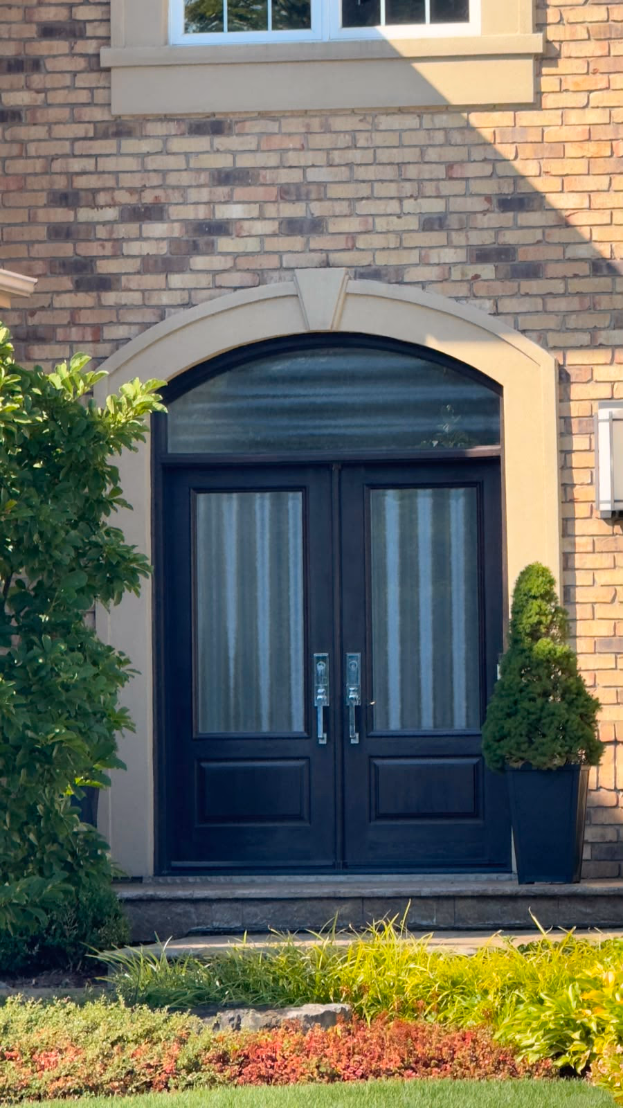 Black double entry doors with glass panels and an arched transom