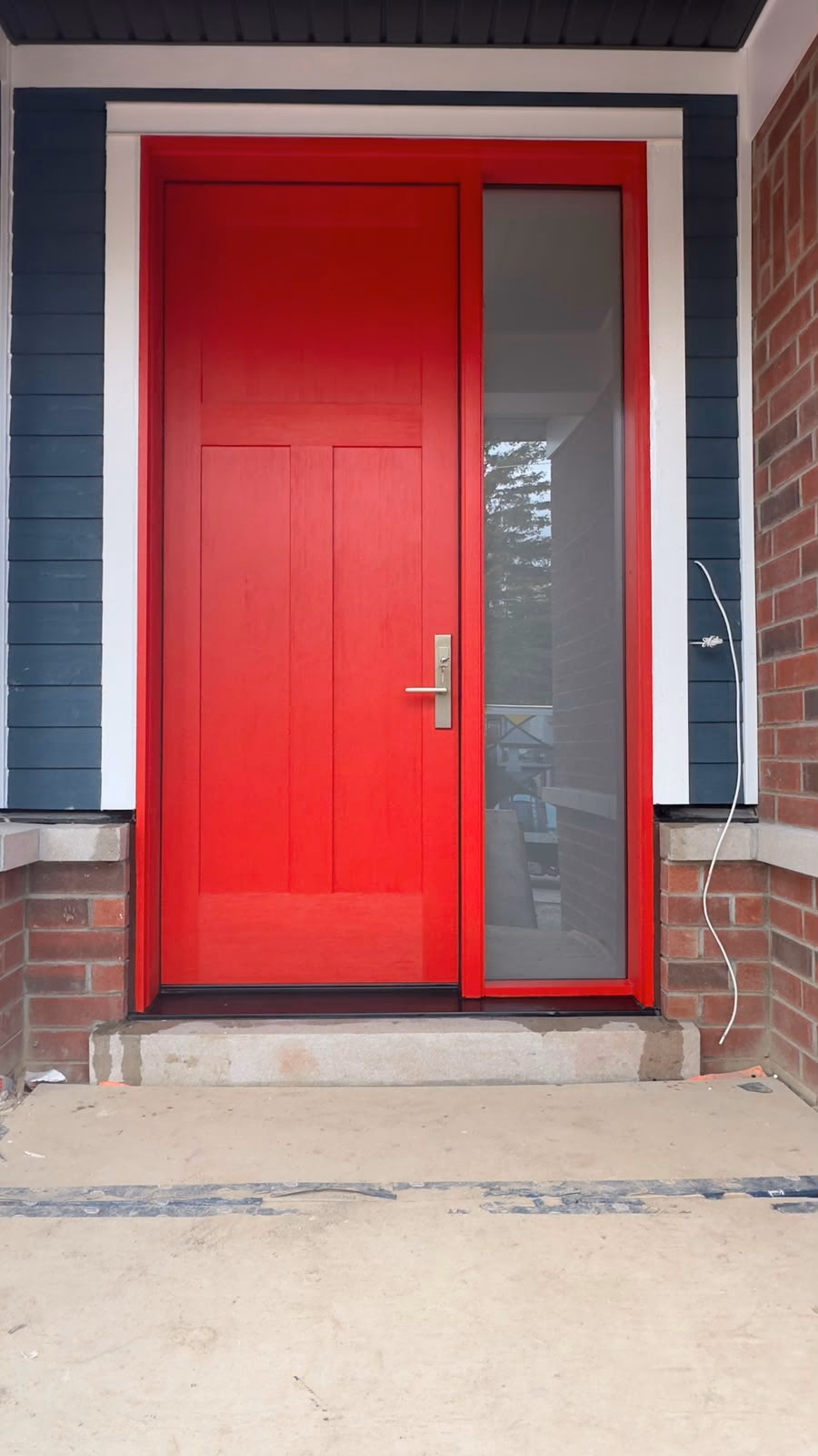 Red entry door with a full-height glass sidelight